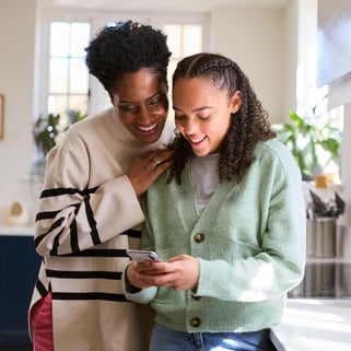 Mom and daughter looking at cellphone to review purchases