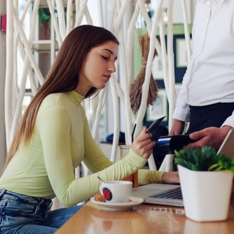 Teen using debit card to check out at a coffee shop